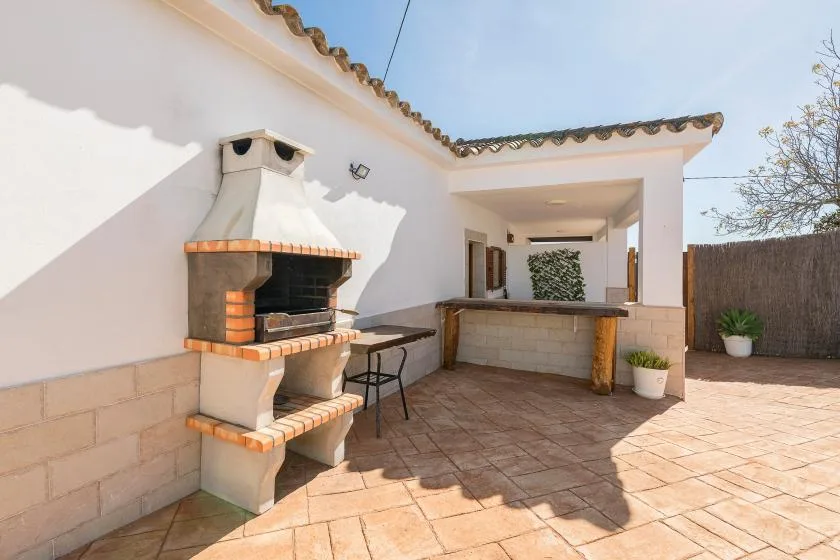 A tiled outdoor patio with a brick barbecue and a covered counter.