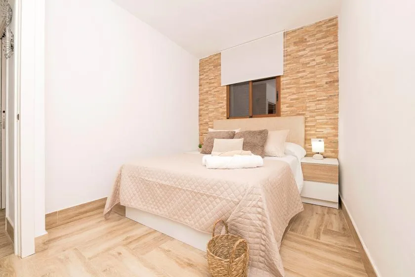 A bedroom with a neatly made bed and a small bedside table.