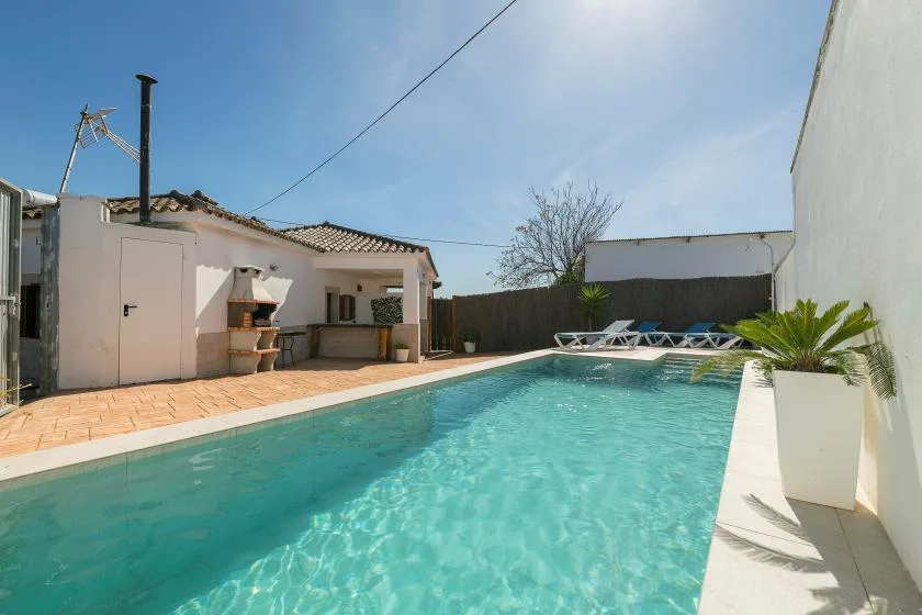 An outdoor swimming pool beside a low white building and paved patio.