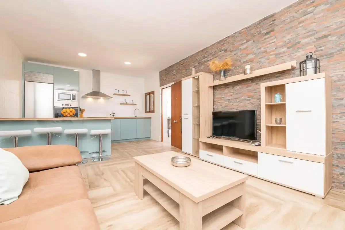 Open-plan living room with a television area and kitchen behind the seating.