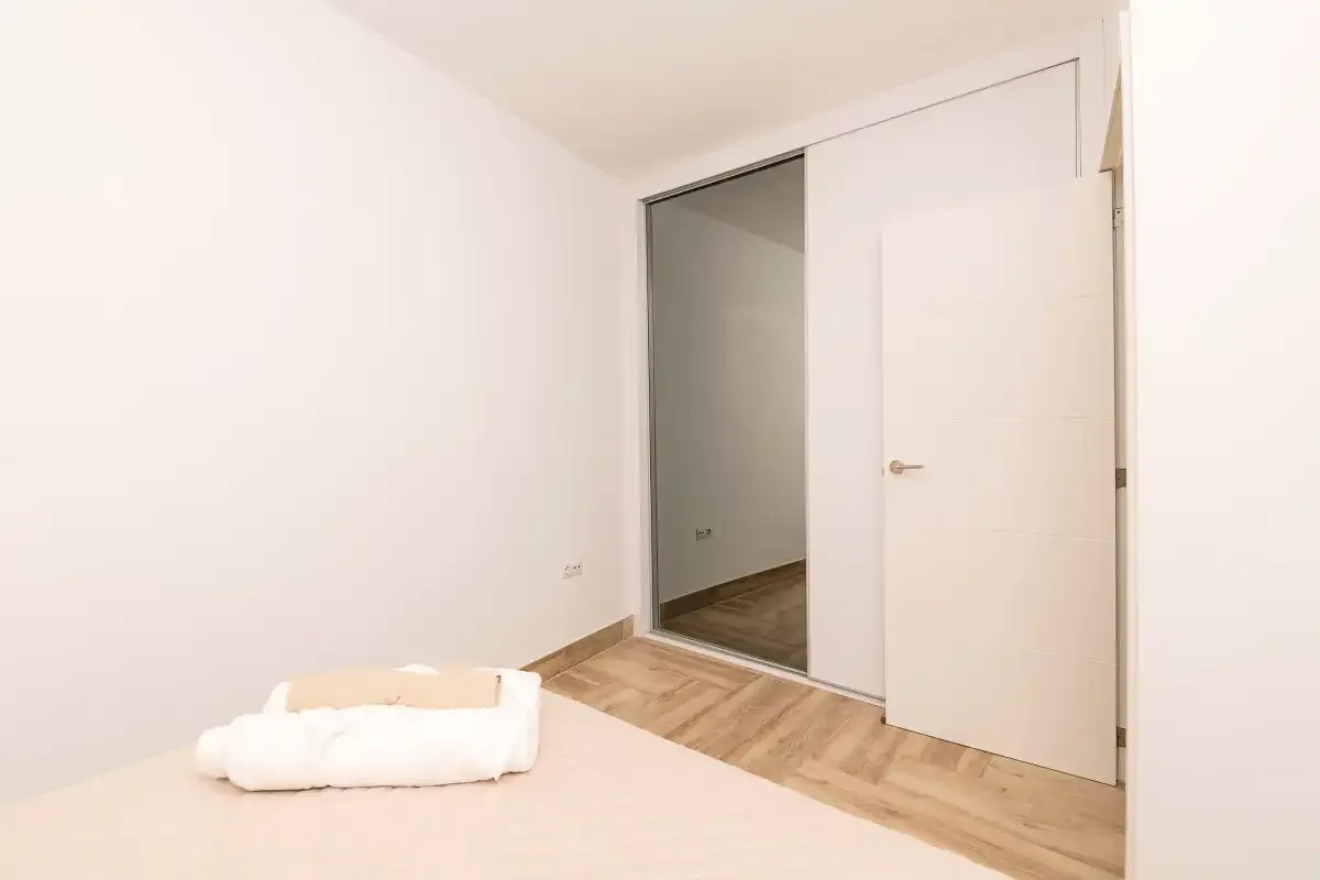 A bright bedroom with a bed beside an open doorway.