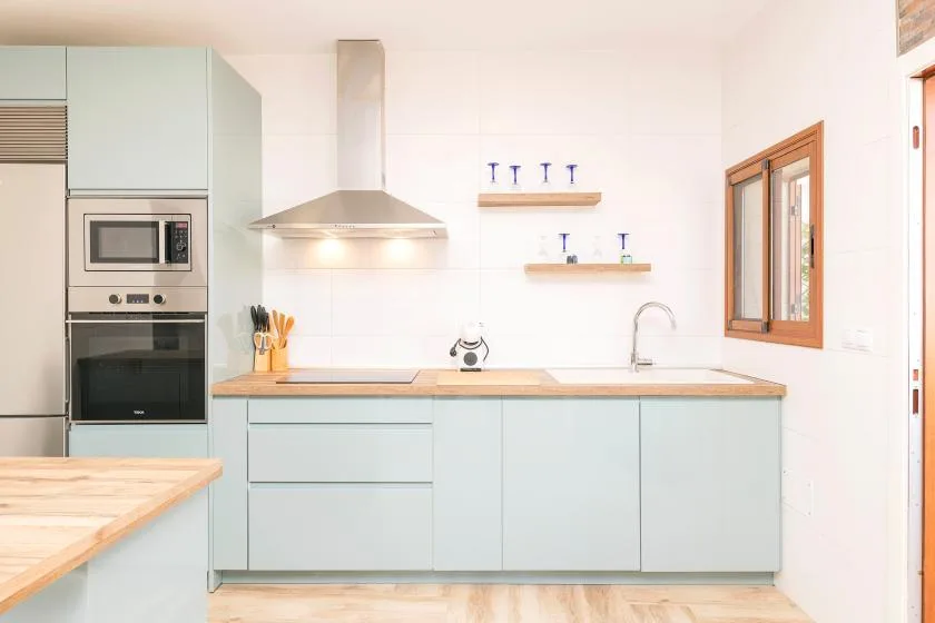 A bright kitchen with pale cabinets, a countertop, and built-in appliances.