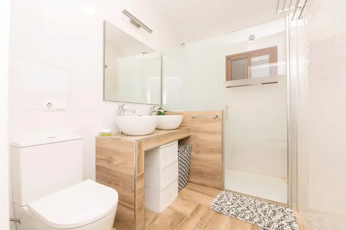 A bright bathroom with a vanity, sink, toilet, and shower.