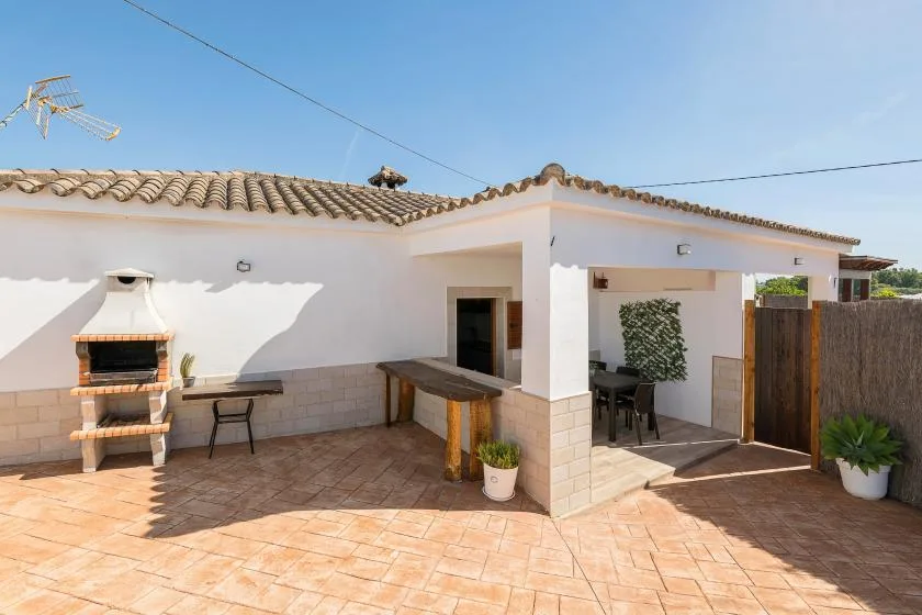 A tiled outdoor patio with a built-in barbecue and covered seating area.