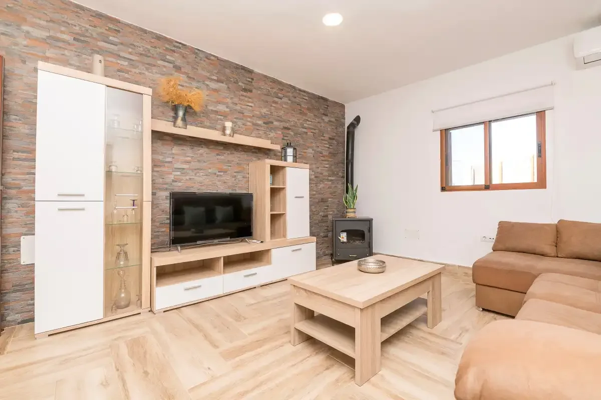A living room with a television, coffee table, and tan seating.