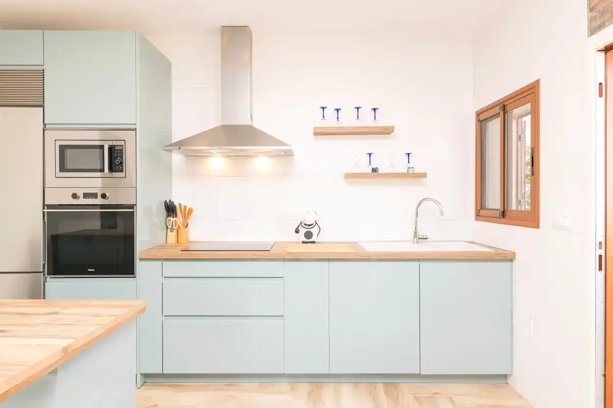 A bright kitchen with pale cabinets, a cooktop, and a countertop.