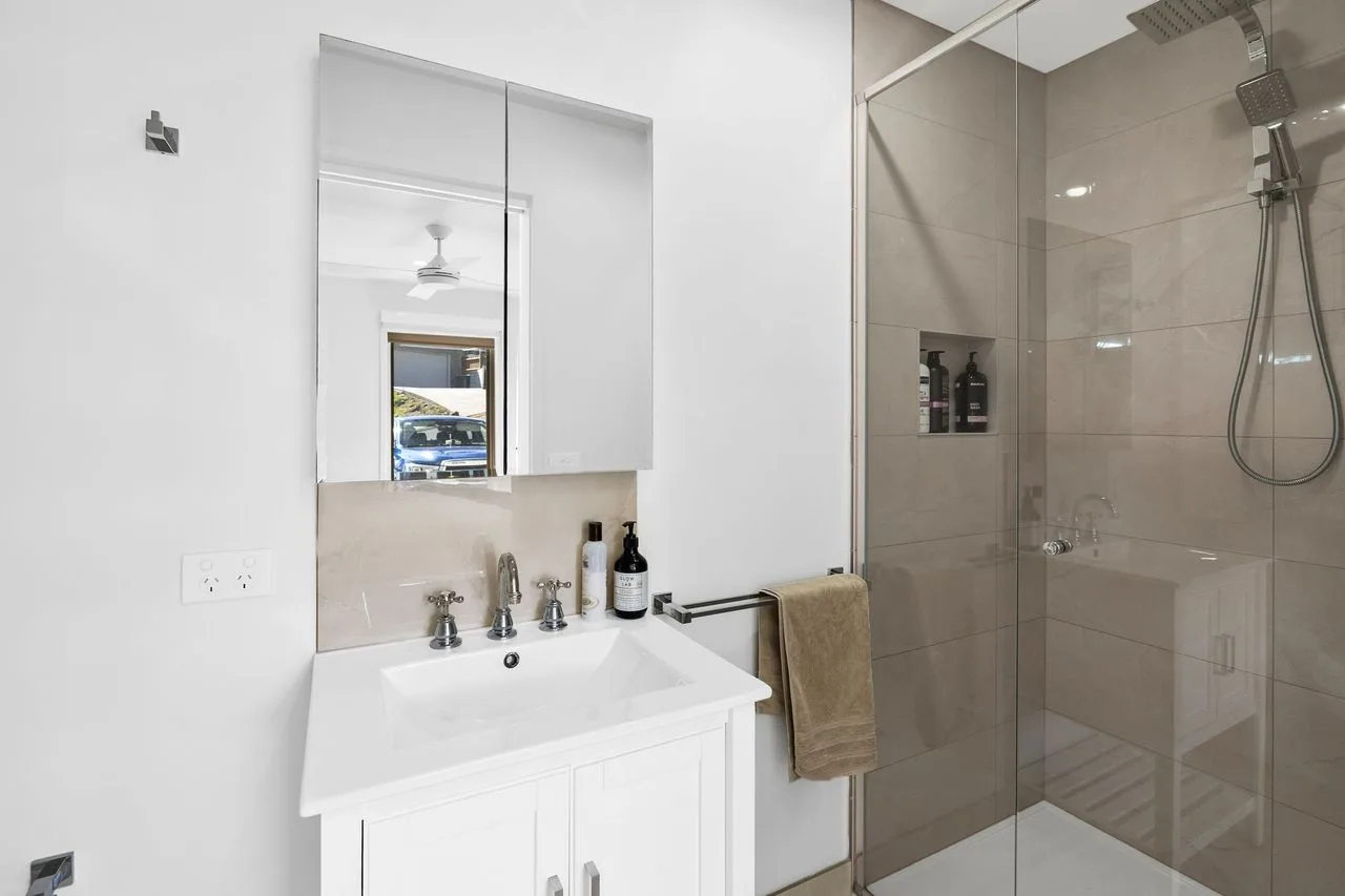 Un lavabo de baño con espejo está junto a una ducha de vidrio.