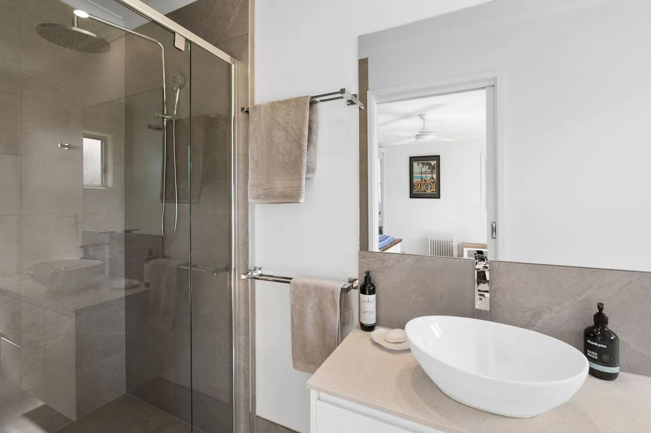 Baño con una ducha de vidrio y un lavabo blanco.