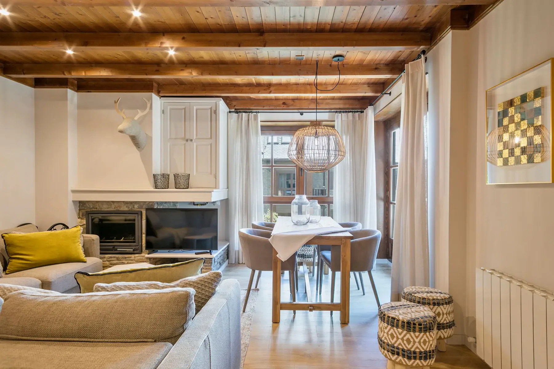 A living room with seating, a fireplace, and a dining table beside large windows.