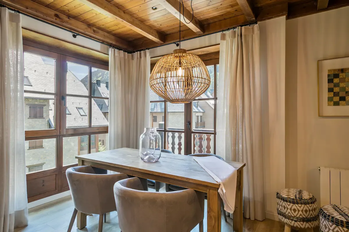 A dining area with a wooden table beneath a woven pendant light.