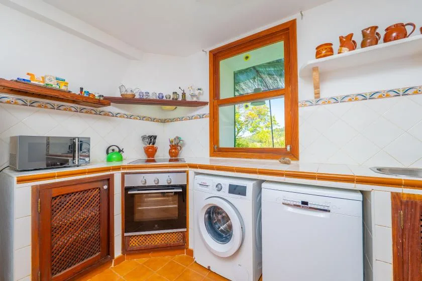 A bright kitchen with a washing machine and a window above the counter.