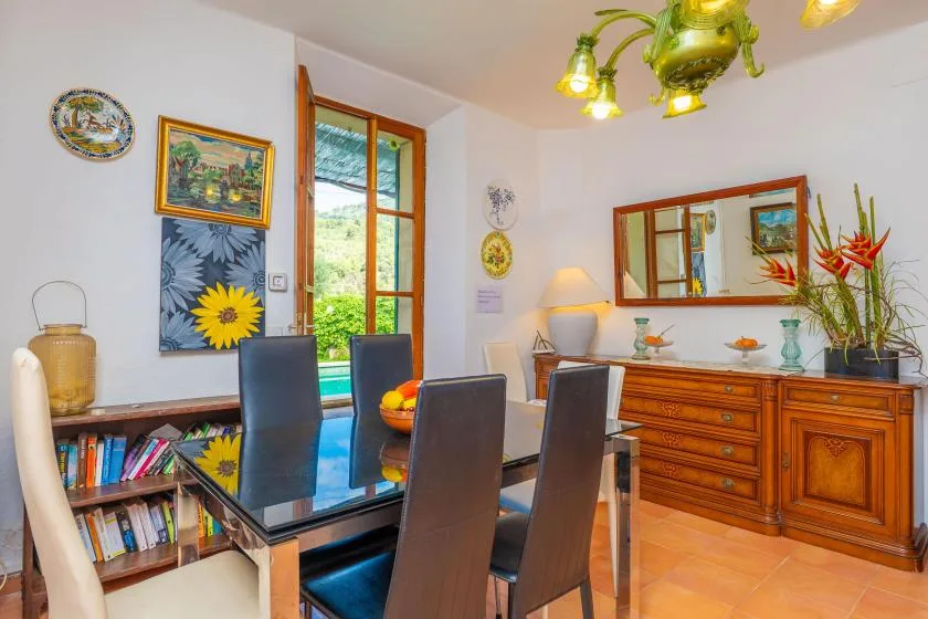 A dining room with a glass table and wooden sideboard.
