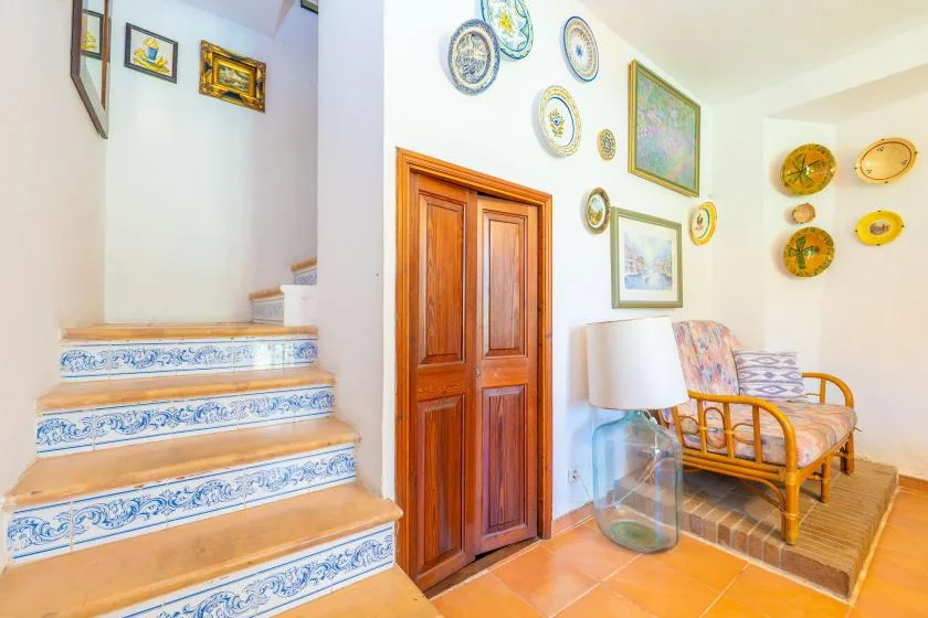 A bright interior with a tiled staircase, wooden door, and seating area.