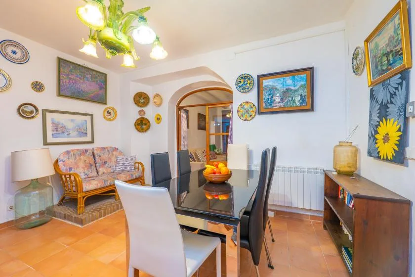 A dining area with a glass table and colorful artwork on the walls.