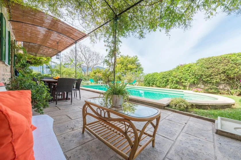 An outdoor patio with seating overlooks a swimming pool and garden.