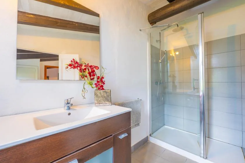 A bathroom with a sink vanity, wall mirror, and glass shower.