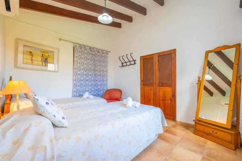 A bedroom with a bed, a wooden wardrobe, and a full-length mirror.