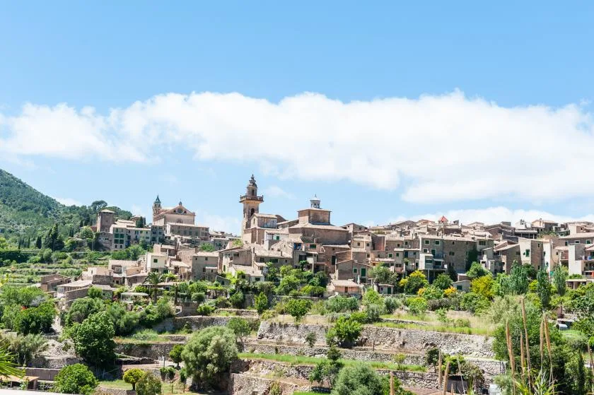 A hillside town with clustered buildings rises above green terraces.