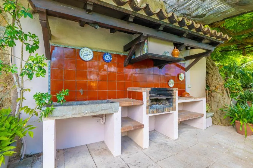 An outdoor barbecue area with a tiled backsplash, built-in grill, and work counters.