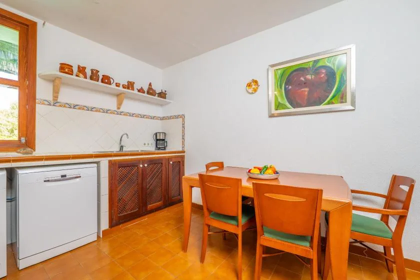 A dining area with a wooden table and chairs beside a compact kitchen.