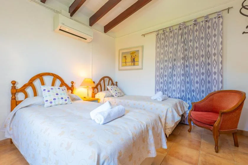 A bedroom with two beds and a red upholstered armchair.