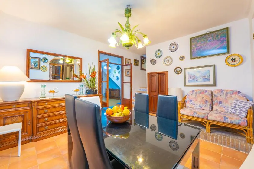 A dining room with a glass table, upholstered seating, and colorful wall art.