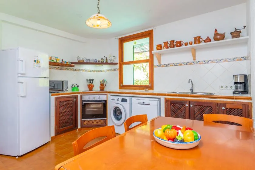 A bright kitchen with wooden cabinets, appliances, and a dining table.