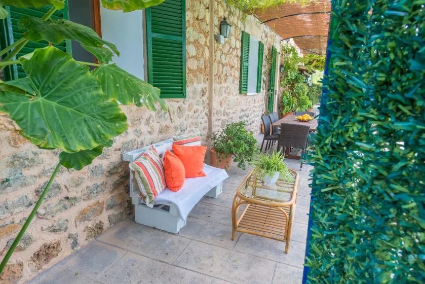 A stone-walled patio with cushioned seating and potted plants.
