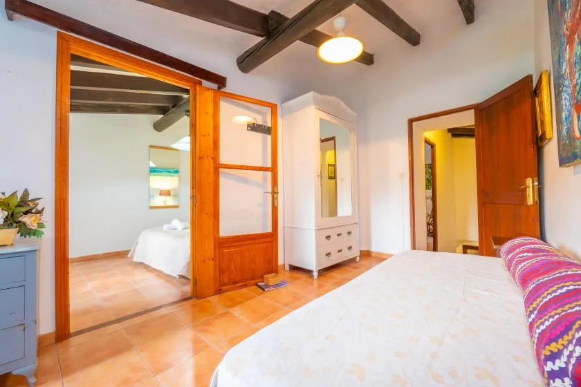 A bedroom with a bed, exposed ceiling beams, and wooden doors.