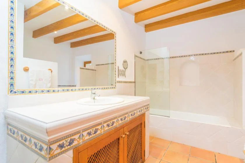 A tiled bathroom with a wide vanity and a glass shower.