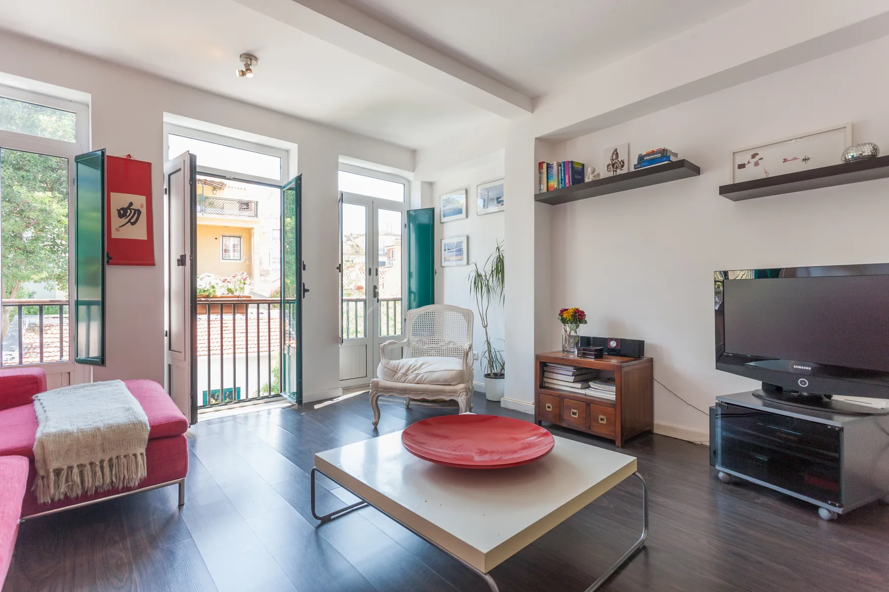 Una sala de estar luminosa con televisor y asientos junto a ventanas altas.