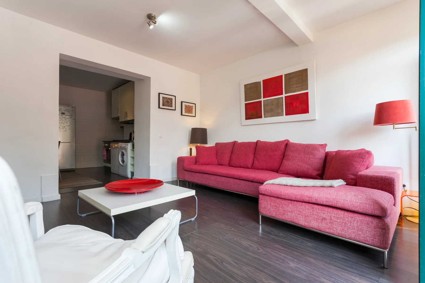 Una sala de estar con un sofá seccional rosa y una mesa de centro blanca.