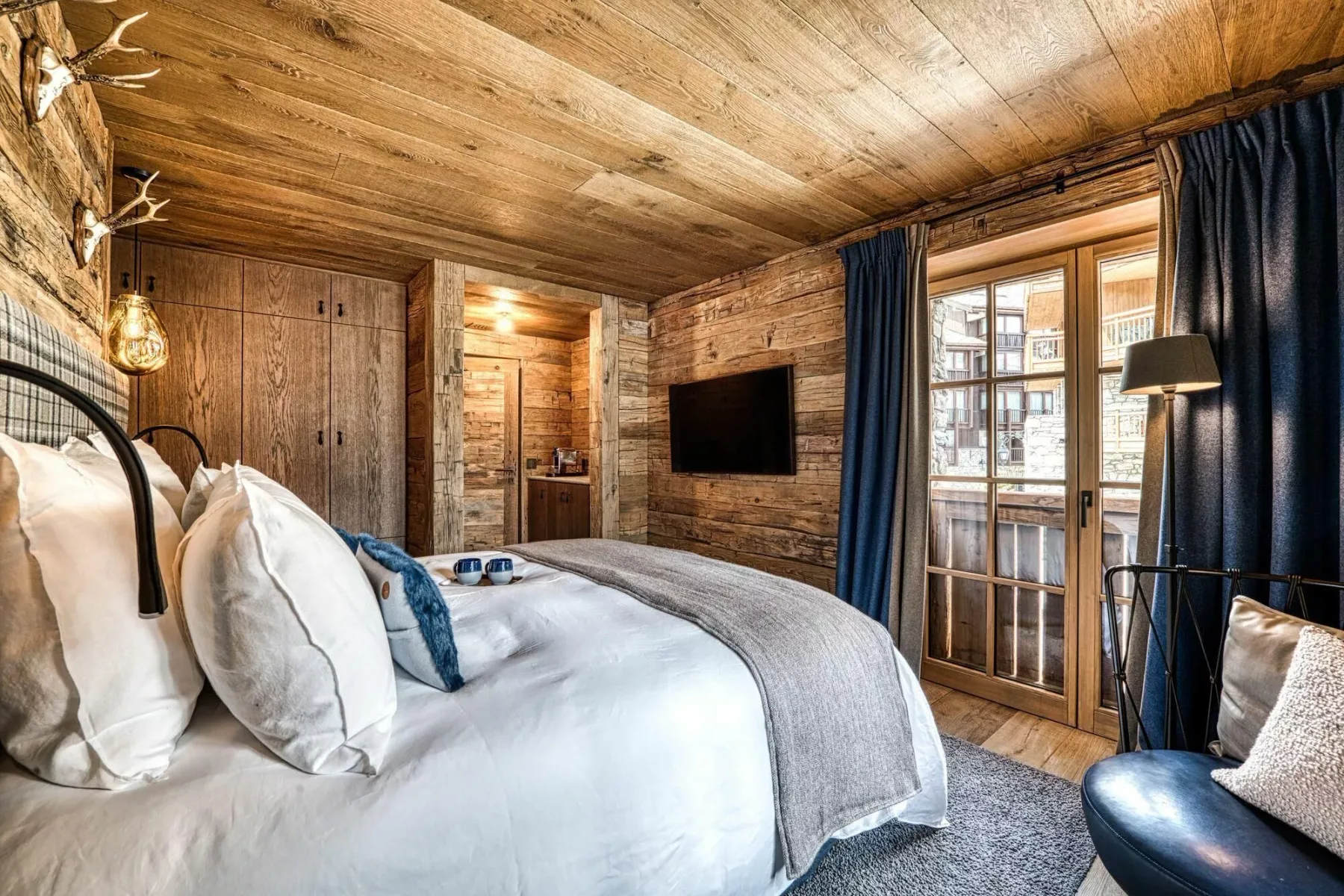 A wood-paneled bedroom with a bed and glass doors opening onto a balcony.