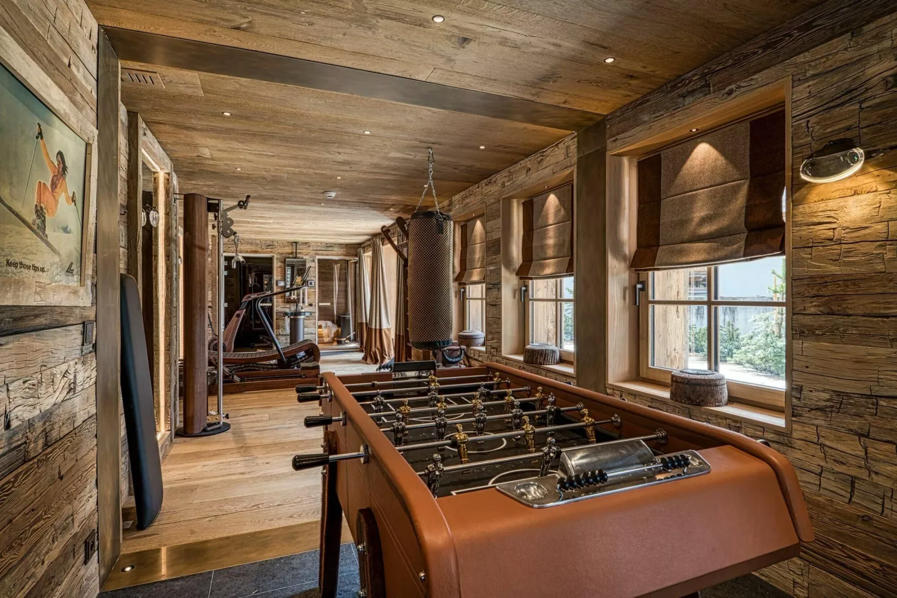 A wooden recreation room with a foosball table and exercise equipment.
