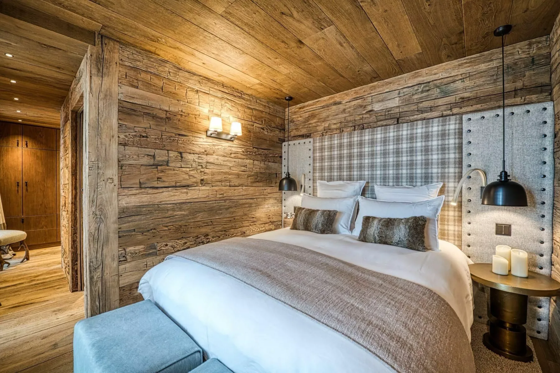 A bedroom with a large bed, upholstered headboard, and wood-paneled walls.