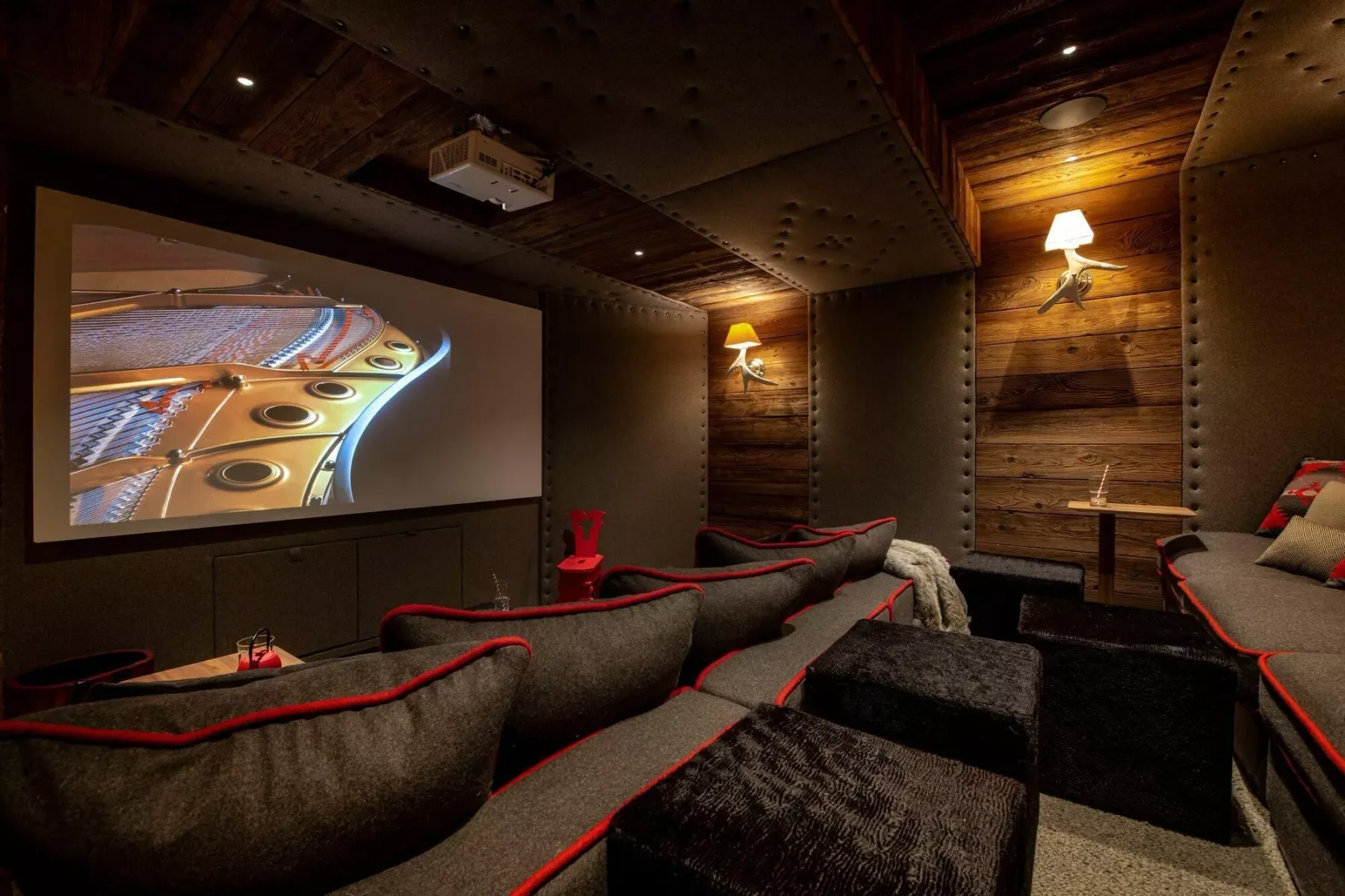 A home theater with tiered seating and a large screen showing a piano.