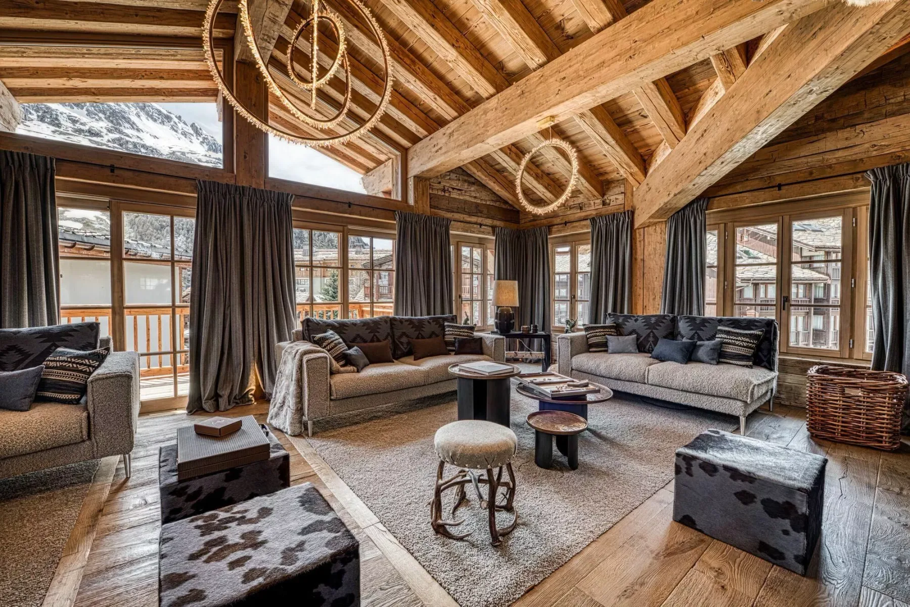 A spacious living room with seating arranged around a coffee table beneath a timber ceiling.
