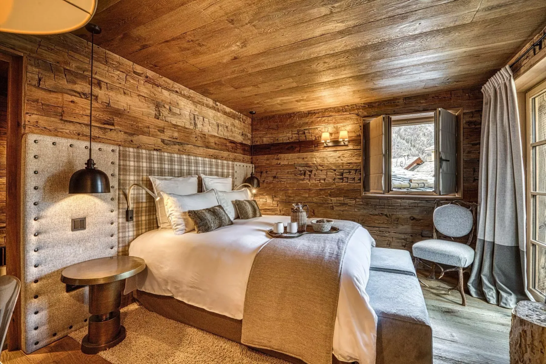 A bedroom with a large bed, wood-paneled walls, and a window.