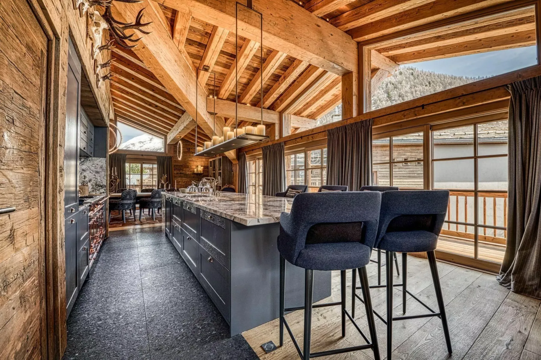 A kitchen and dining area with a long island and large windows.