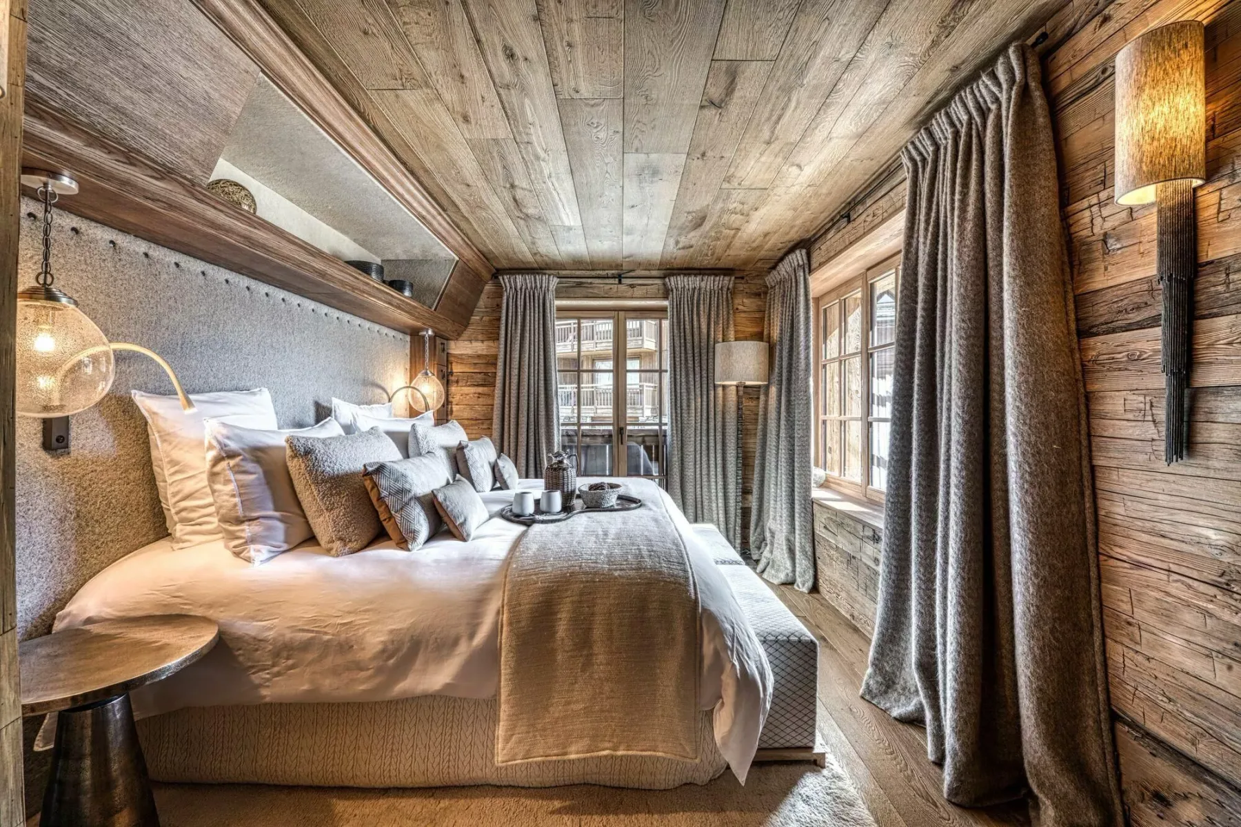 A bedroom with a bed and large windows.