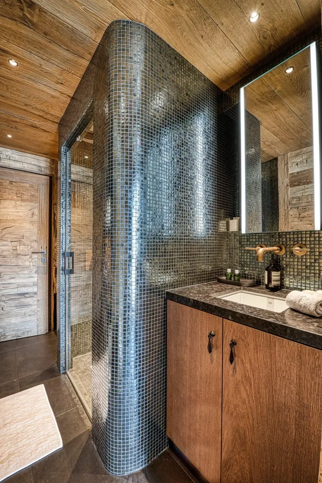 A bathroom with a tiled shower, vanity, and wood-paneled ceiling.