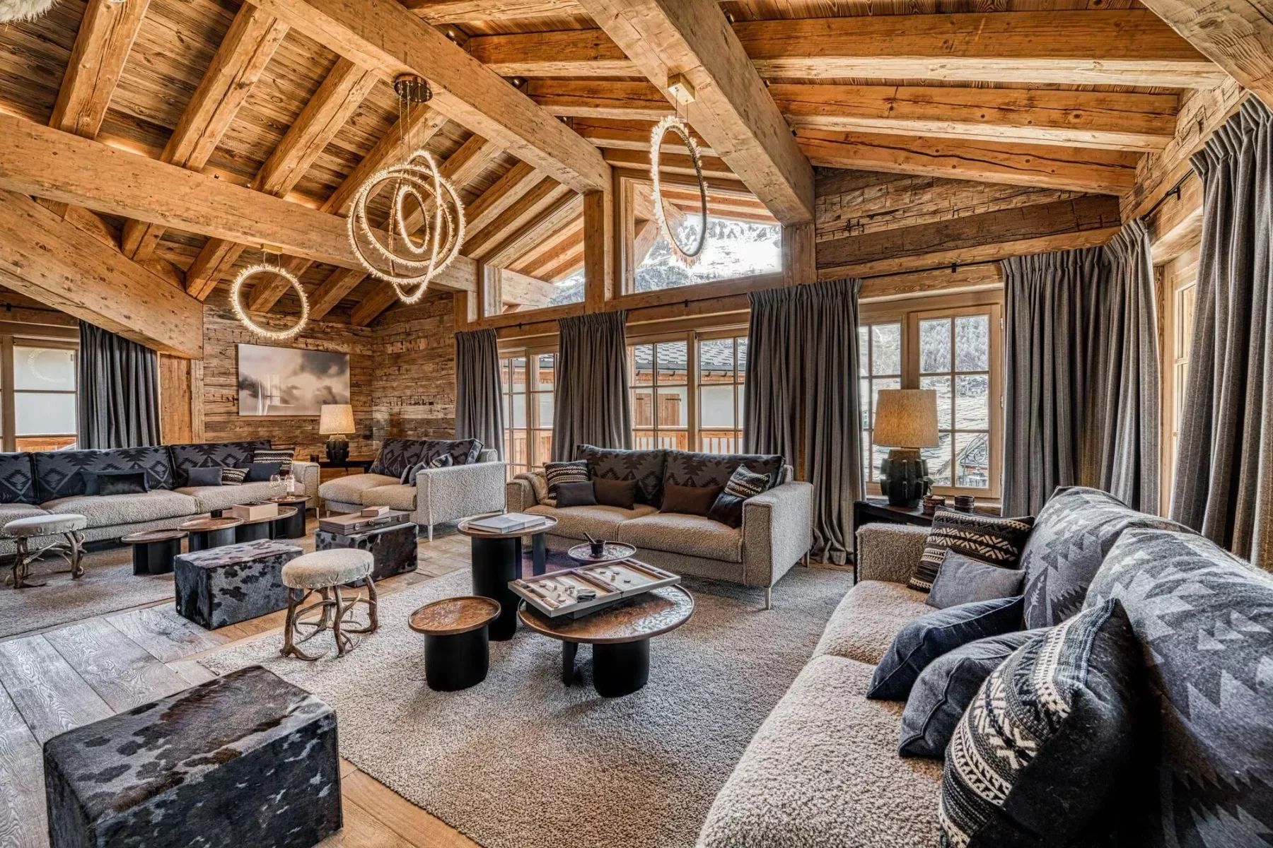 A spacious living room with seating arranged beneath exposed wooden beams.
