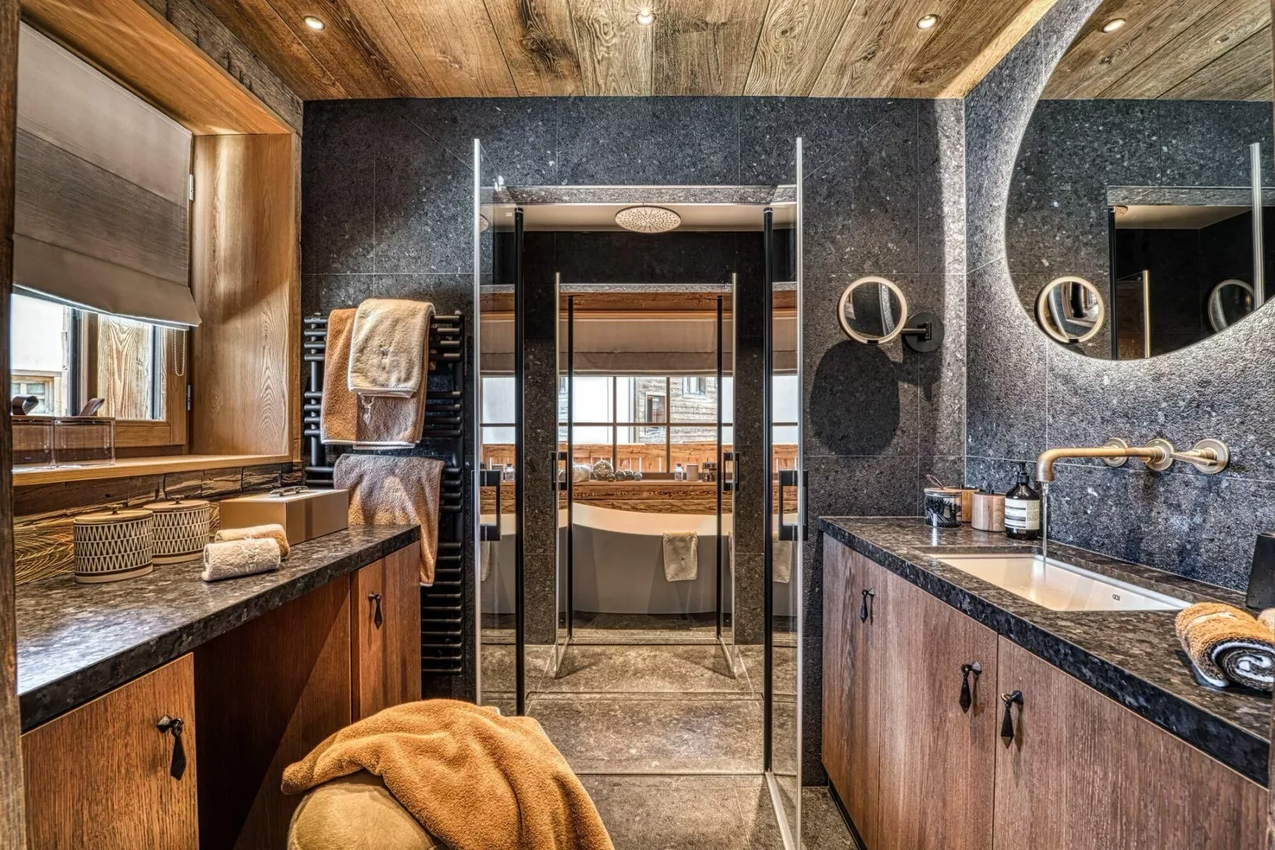 A bathroom with a bathtub, a glass shower enclosure, and dark stone counters.