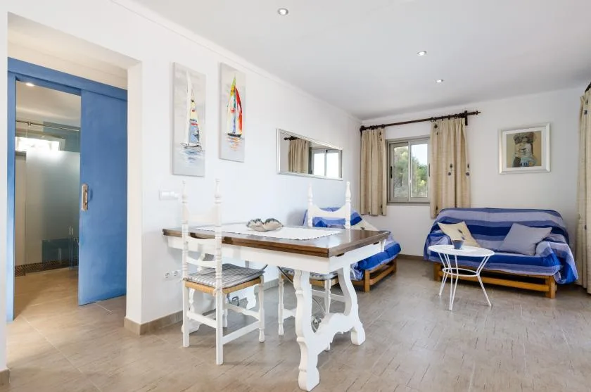 Una luminosa sala de estar con una mesa de comedor y asientos azules junto a la ventana.
