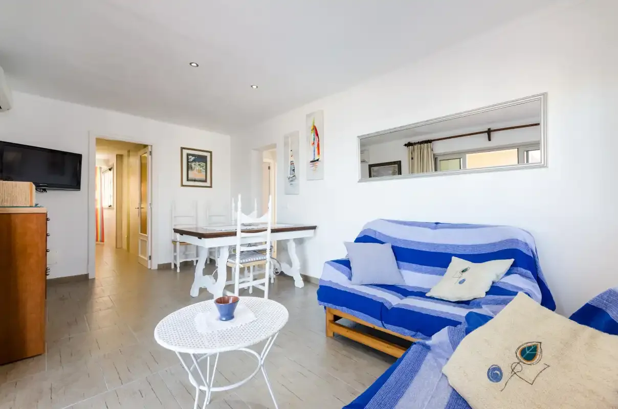 Una luminosa sala de estar y comedor con asientos azules y una mesa blanca.