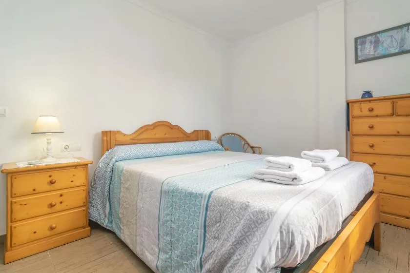 Un dormitorio con una cama de madera vestida con ropa de cama azul claro y blanca.