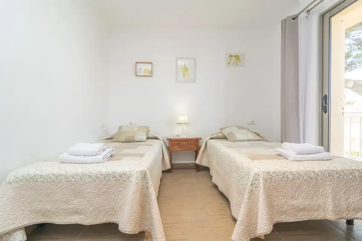 Un dormitorio luminoso con dos camas y una pequeña mesa de noche.