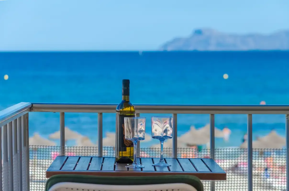 Una mesa de balcón da al mar y a una playa de arena.