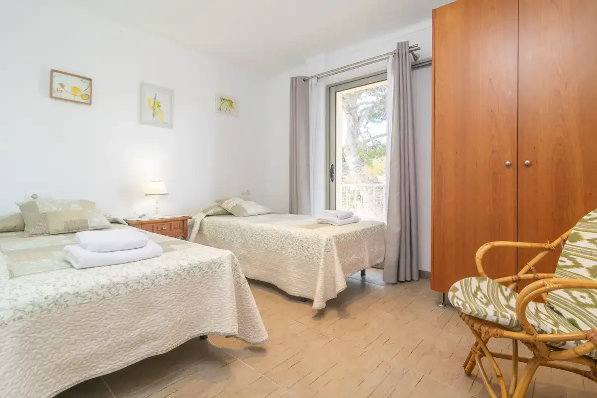 Un dormitorio luminoso con dos camas y un armario grande de madera.
