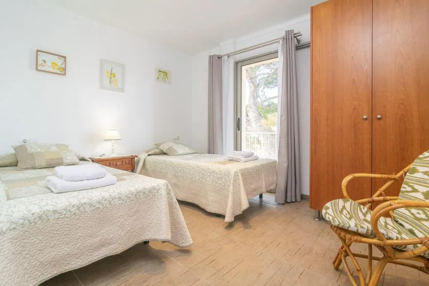 Un dormitorio con dos camas, un armario y una ventana con cortinas.